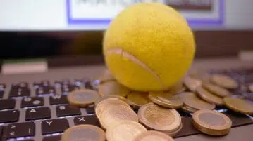 Une balle de tenis et des sous sur un ordinateur